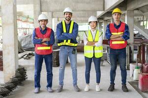 engineering teamwork in full safety gear,standing arms crossed,in the building under construction that filled with many construction equipment.concept of engineering work,engineer working on site work photo