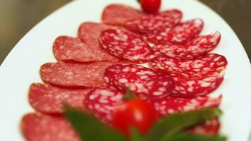 affettato salame, prosciutto salsiccia su un' bianca piatto. cibo concetto. buffet tavolo nel un' Hotel o ristorante su vacanza. video