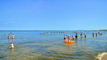 Swinoujscie, Poland. 15 August 2023. People in the water on the beach during holiday season in over Baltic Sea. photo