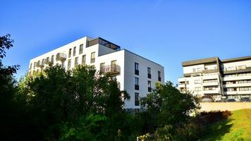 Modern apartment building and green trees. Ecological housing architecture. A modern residential building in the vicinity of trees. Ecology and green living in city, urban environment photo