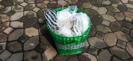 Waste basket full of rubbish, close-up. Disposable cups and other plastic waste in the trash can. photo