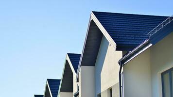 Suburban neighborhood with condominium complex. Suburban area with modern geometric family houses. Row of family houses against blue sky. photo