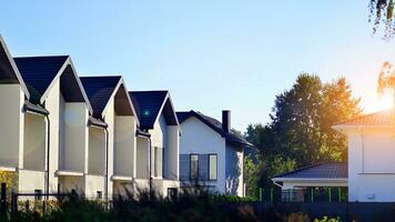 Suburban neighborhood with condominium complex. Suburban area with modern geometric family houses. Row of family houses against blue sky. photo