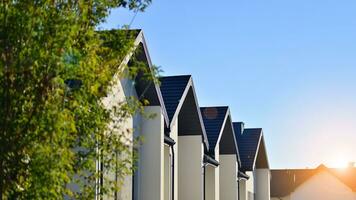 Suburban neighborhood with condominium complex. Suburban area with modern geometric family houses. Row of family houses against blue sky. photo