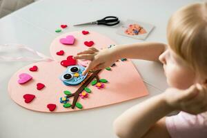 A blogger girl makes a felt craft for Valentine's Day in the shape of a heart. The concept of children's creativity and handmade. photo