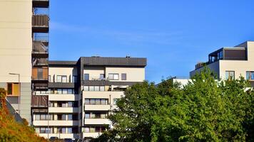 Modern apartment building and green trees. Ecological housing architecture. A modern residential building in the vicinity of trees. Ecology and green living in city, urban environment photo