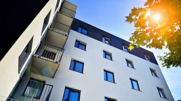 Modern apartment building and green trees. Ecological housing architecture. A modern residential building in the vicinity of trees. Ecology and green living in city, urban environment photo