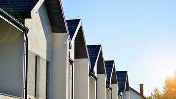 Suburban neighborhood with condominium complex. Suburban area with modern geometric family houses. Row of family houses against blue sky. photo