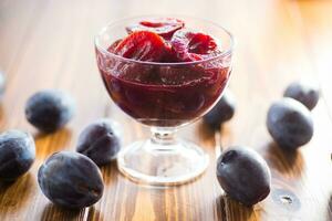 Sweet plums in syrup, in a glass bowl . photo