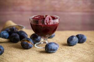 Sweet plums in syrup, in a glass bowl . photo