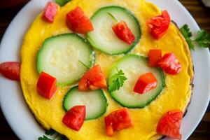 Fried omelet with zucchini, tomatoes, herbs in a plate photo