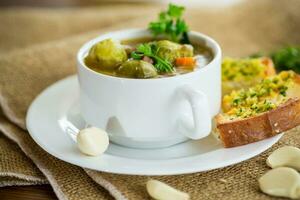 Hot cooked soup with Brussels sprouts, vegetables and croutons, in a plate. photo