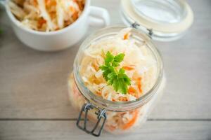 Sauerkraut with carrots and spices in a glass jar photo