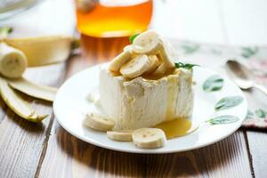 Portion of homemade milk curd with banana slices and honey photo