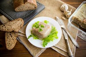 Boiled chicken meat aspic in meat gelatin broth in a plate photo