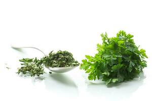 dried parsley in a spoon next to fresh herbs. photo