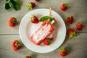 homemade strawberry ice cream on a stick in a plate with strawberries photo