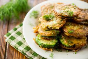 zucchini fried in circles in batter with herbs, in a plate . photo