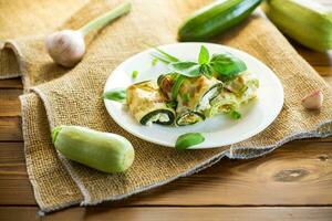 cooked zucchini rolls with cheese filling inside, in a plate photo