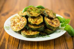 zucchini fried in circles with spices and herbs, in a plate . photo