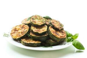 zucchini fried in circles with spices and herbs, in a plate . photo