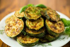 zucchini fried in circles with spices and herbs, in a plate . photo