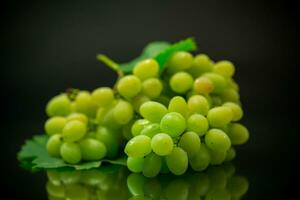 A bunch of ripe green grapes with leaves. photo
