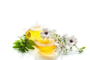 Chamomile flower tea in glass cup and teapot, on white background. photo