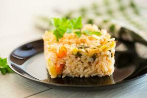 Cooked boiled rice with zucchini, carrots and vegetables in a plate photo