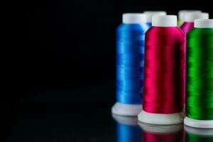 set of different color sewing threads,on black background. photo