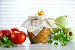 Cooked zucchini caviar with tomatoes in a glass jar,. photo