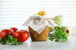 Cooked zucchini caviar with tomatoes in a glass jar,. photo