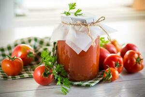Cooked homemade tomato juice canned in a jar of natural tomatoes. photo