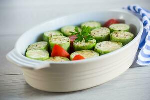 Raw zucchini with tomatoes prepared for baking in a ceramic form. photo