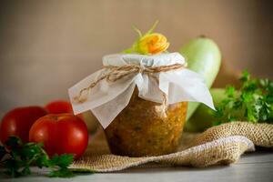 Cooked zucchini caviar with tomatoes in a glass jar,. photo
