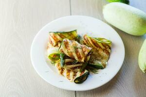 Grilled zucchini pieces with garlic sauce in a white plate. photo