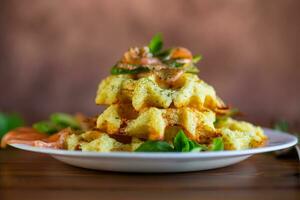 Cooked potato waffles with lightly salted red fish and herbs in a plate. photo