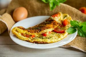 Stuffed omelette with tomatoes on a light wooden background. photo