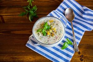 Cold soup with cucumbers, eggs, vegetables, yogurt and fresh herbs in a glass bowl . photo