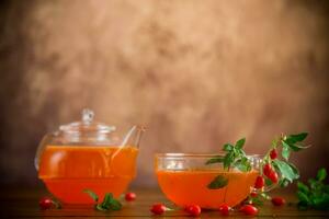 Prepared drink from ripe goji berries in a glass cup and teapot photo