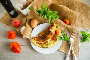 Stuffed omelette with tomatoes on a light wooden background. photo