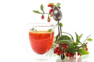 Prepared hot drink from ripe goji berries in a glass cup photo