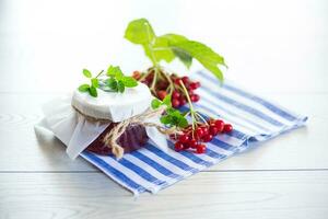 viburnum jam in a glass jar and fresh red viburnum. photo