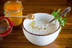 milk oatmeal porridge with honey for breakfast in a bowl wooden table. photo