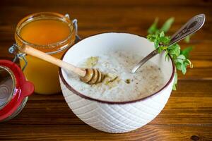milk oatmeal porridge with honey for breakfast in a bowl wooden table. photo