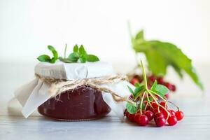 viburnum jam in a glass jar and fresh red viburnum. photo