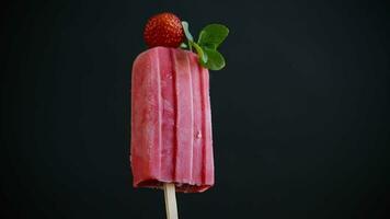 gekocht hausgemacht Erdbeere Eis Sahne auf ein Stock, isoliert auf schwarz Hintergrund video
