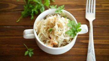 Sauerkraut with carrots and spices in a bowl on a wooden table. video