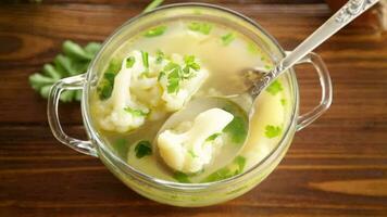 cooked chicken soup with cauliflower and vegetables in a bowl on a wooden table video