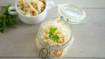 Sauerkraut with carrots and spices in a bowl on a wooden table. video